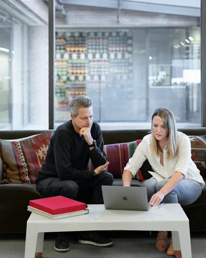 A couple around fifty on a sofa, working through figures together on a laptop.